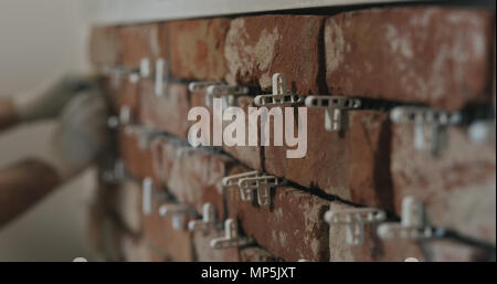 closeup worker applying brick cuts tile on the wall Stock Photo