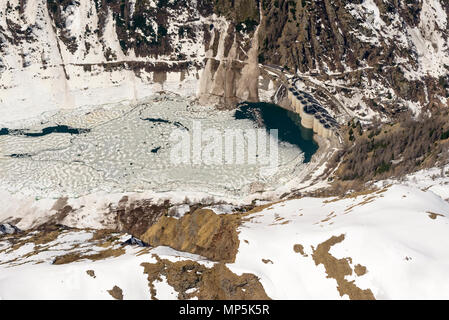 aerial shot, from a small plane, of big dam and melting ice on Vanina lake, shot on a bright springtime day in Orobie mountains, Sondrio , Italy Stock Photo