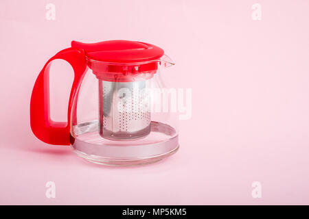 Heat resistant glass teapot with tea strainer on pink Stock Photo
