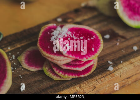 Watermelon Radishes Sliced, Sprinkled with Sea Salt on a wooden background Stock Photo