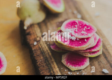 Watermelon Radishes Sliced, Sprinkled with Sea Salt on a wooden background Stock Photo