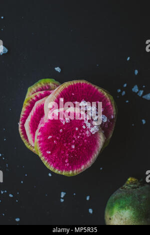 Watermelon Radishes Sliced, Sprinkled with Sea Salt on a black background Stock Photo