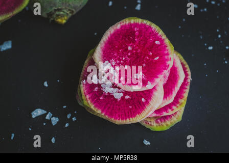 Watermelon Radishes Sliced, Sprinkled with Sea Salt on a black background Stock Photo