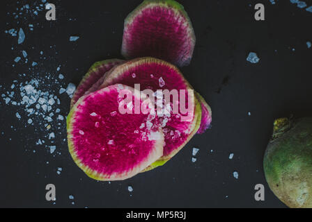 Watermelon Radishes Sliced, Sprinkled with Sea Salt on a black background Stock Photo