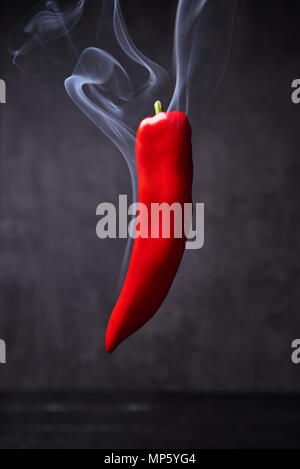 Smoking red hot pepper. Smoked paprika on black background with copy space. Stock Photo
