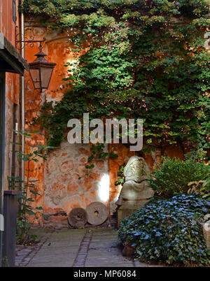 Quet vintage Backyard in Copenhagen, Denmark. Old scandinavian house, cobblestone, vintage street lantern and stone sculpture decorated yard Stock Photo