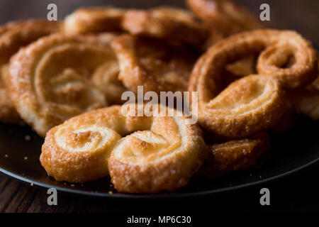 Palmier Cookies in Black Plate on Wooden Surface. Dessert Concept. Stock Photo