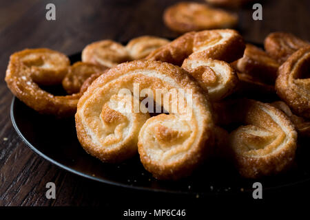 Palmier Cookies in Black Plate on Wooden Surface. Dessert Concept. Stock Photo