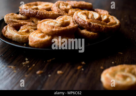 Palmier Cookies in Black Plate on Wooden Surface. Dessert Concept. Stock Photo