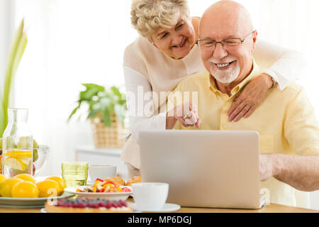 Smiling senior man using laptop with his happy wife. Elderly people using the Internet concept Stock Photo