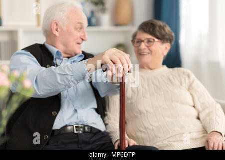 Elderly man with a walking stick talking to his wife