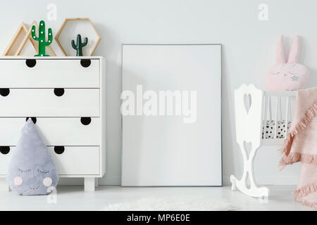 Poster with mockup between white cradle and cabinet in child's room interior. Real photo. Place for your poster Stock Photo