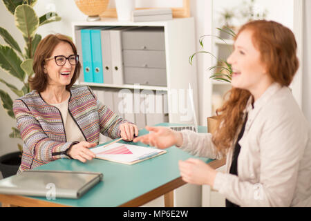 Two women laughing during a job interview in an office