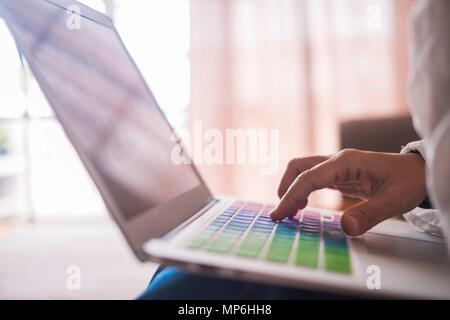 woman hand close up caucasian people work at home with a laptop sitting on the sofa with a window light on the background. colored keyboard and typewr Stock Photo