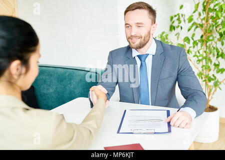 Handsome Businessman Shaking Hands with Partner at Meeting Table Stock Photo