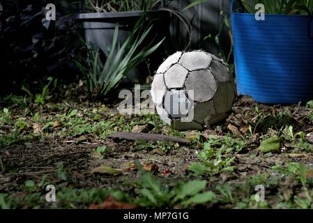 Torn up old soccer ball lay on grass. Worn out football. Concept of inactive person or useless object. Stock Photo