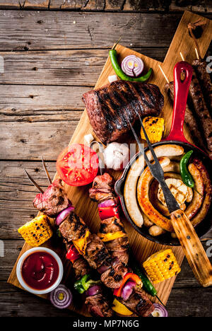 Assortment various barbecue food grill meat, bbq party fest - shish kebab, sausages, grilled meat fillet, fresh vegetables, sauces, spices, on old woo Stock Photo