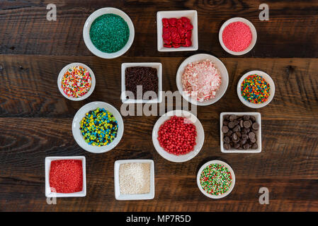 Array of Sprinkles in White Bowls Over Wooden backdrop Stock Photo