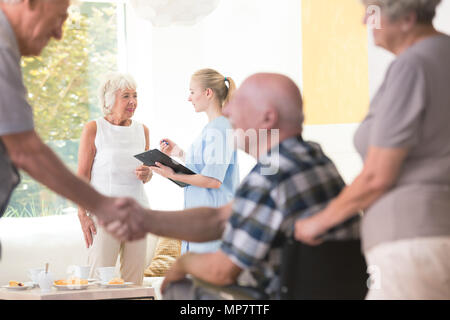 Senior woman talking with a nurse during meeting in living room of rest house Stock Photo