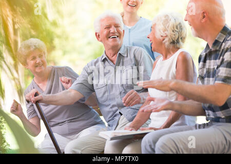 Group of smiling senior friends spending time together sitting in the park Stock Photo