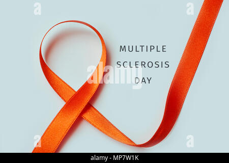 the text multiple sclerosis day and an orange ribbon on an off-white background Stock Photo