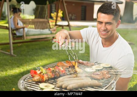 Shot of a young man tending a barbecue Stock Photo