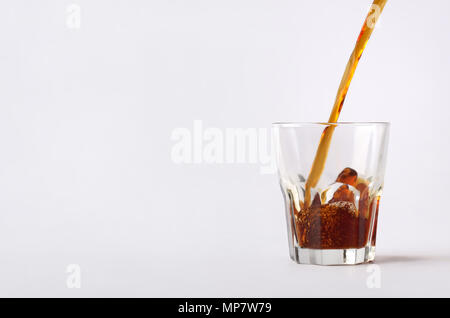 The close-up composition with the dynamic flow of hot coffee  beverage is poured on the glass cup.Image isolated on the white background. Stock Photo