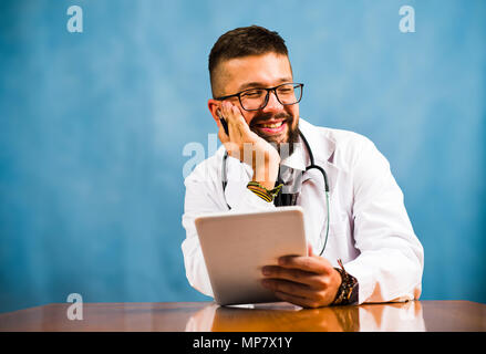 Male doctor holding digital tablet in office desk Stock Photo