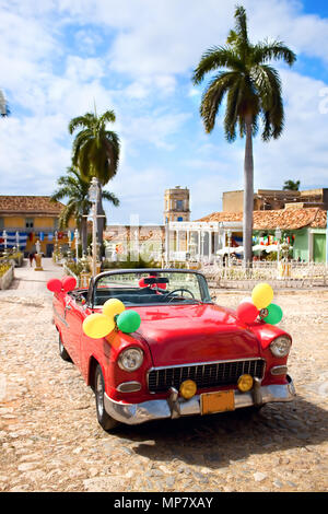 TRINIDAD, CUBA -14 JANUARY: Red oldtimer car in the central square of Trinidad on January 14. 2010. Trinidad, Cuba. Stock Photo