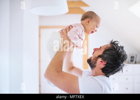 Father with a toddler girl in bedroom at home, having fun.