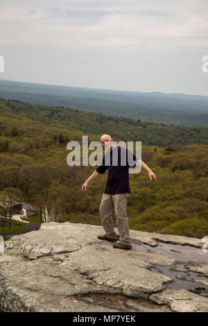 Senior male hiker standing on Sam's Point Overlook, Ulster County, New York pretending to fall over ledge. Stock Photo