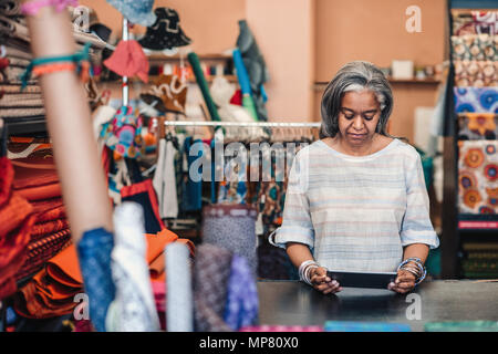 Mature woman using a digital tablet in her fabric store Stock Photo