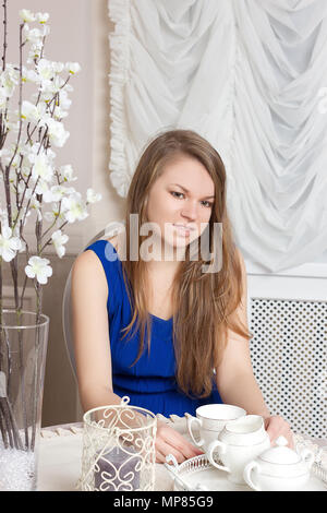 Smiling beautiful girl in  dress sits at table in cosy cafe. Stock Photo