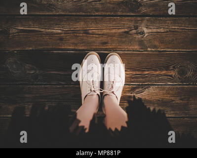 Selfie of feet in fashion beige leather flat brogues shoes on old wooden background, top view. Girl in pleated skirt. Trendy look. Hipster film filter Stock Photo