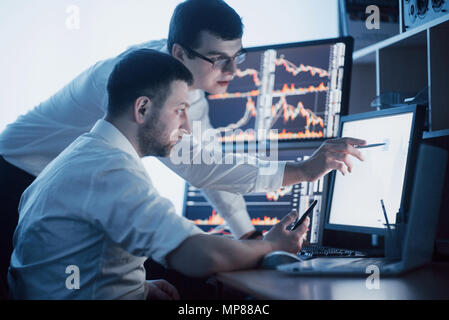 Analyzing data. Close-up of young business team working together in creative office while young woman pointing on the data presented in the chart with pen Stock Photo