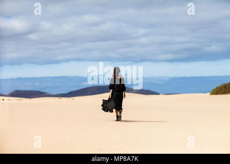 Full length portrait of lonely woman walks away in desert on Canary Islands. Travel concept