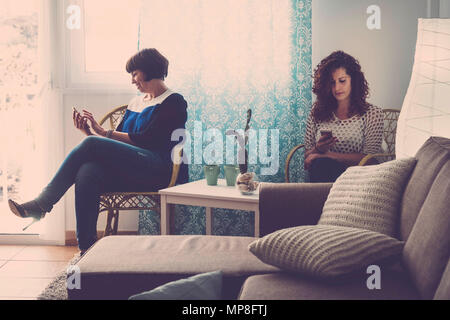 two women friends at home everyone with a mobile phone chat and look or check email. don't speak each other in a modern day. technology destroy friend Stock Photo
