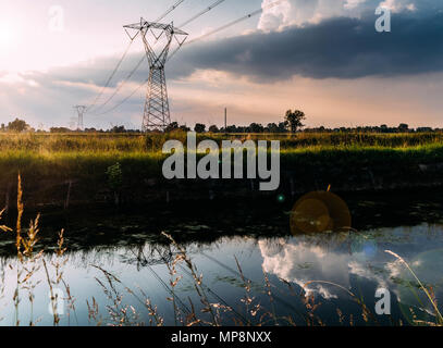 Long exposure of moving water and clouds at sunset overlooking the Naviglio Pavese, Italy. The canal links the city of Milan and Pavia Stock Photo