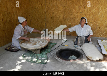 Two women make lavash (a traditional flatbread) by rolling out the dough, then baking in a tandoor oven, Garni, Armenia Stock Photo