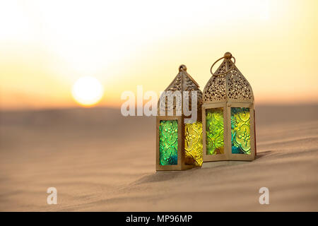 Traditional ornamental arabic lantern with a burning candle in desert during sunset. Festivel greeting card for Ramadan Kareem and Ramadan Mubarak. Du Stock Photo