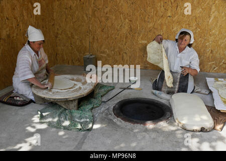 Two women make lavash (a traditional flatbread) by rolling out the dough, then baking in a tandoor oven, Garni, Armenia Stock Photo