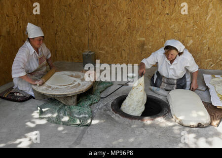 Two women make lavash (a traditional flatbread) by rolling out the dough, then baking in a tandoor oven, Garni, Armenia Stock Photo