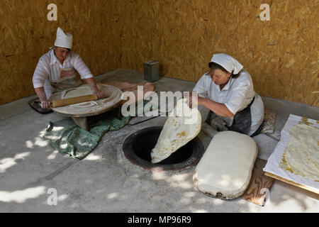 Two women make lavash (a traditional flatbread) by rolling out the dough, then baking in a tandoor oven, Garni, Armenia Stock Photo