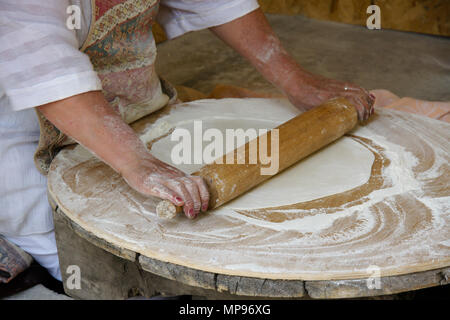A woman rolls dough to make lavash (a traditional flatbread) which will then be baked in a tandoor oven, Garni, Armenia Stock Photo