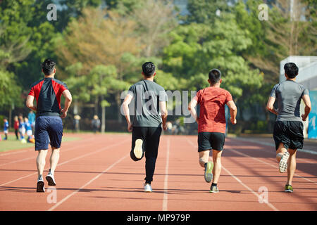 young asian adult athletes running training on track, rear view. Stock Photo