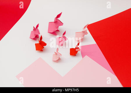 Seven pink origami rabbits on pink and white paper Stock Photo