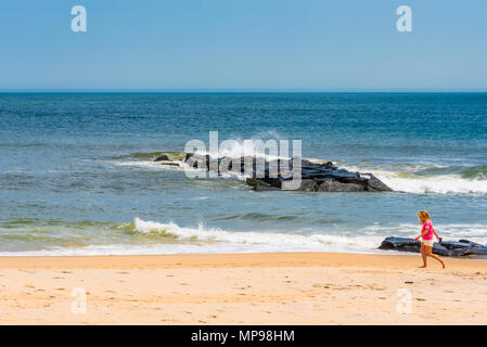 Spring Lake, NJ USA -- May 20, 2018. A young woman goes for a walk on the Spring Lake beach. Stock Photo