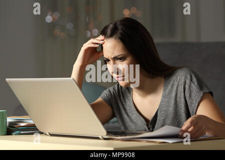 Concentrated self employed working hard online with a laptop in the night at home Stock Photo