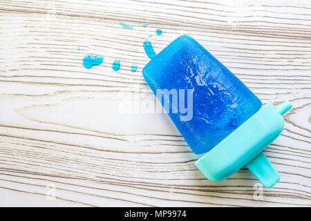 Blue Blueberry popsicle melts on wooden backdrop Stock Photo