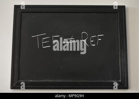 TEF ≠ REF written in white chalk on a black board mounted on a wall. Stock Photo